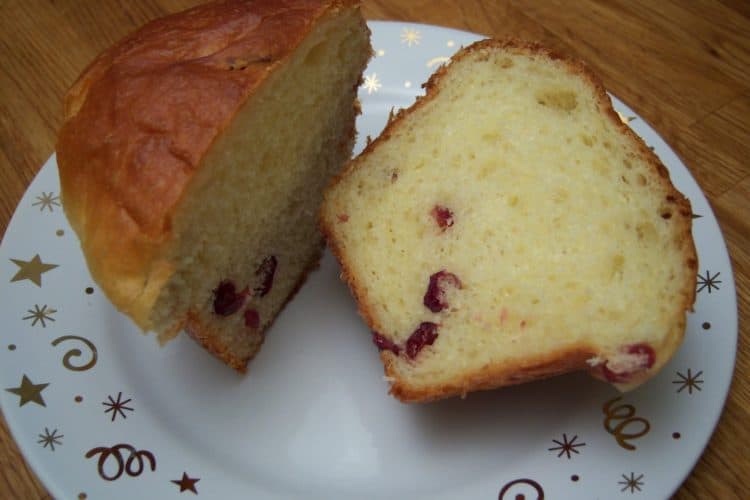 Kugelhopf sliced in half with dried cranberries on small white plate with gold stars and swirls