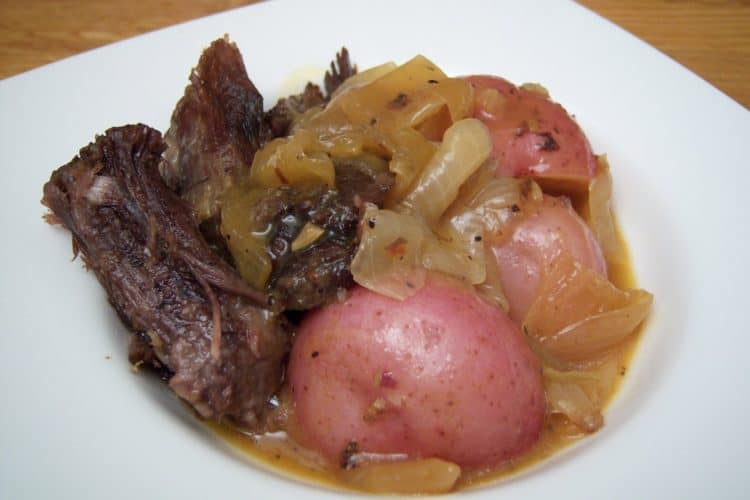 Pot roast with potatoes and onions in white square bowl