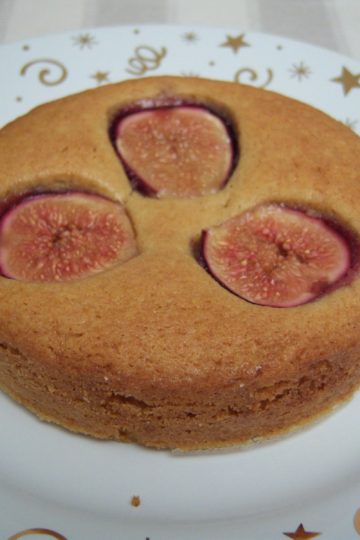 Dimply Fig Cake small round cake with fresh figs on small round white plate with gold stars and swirls