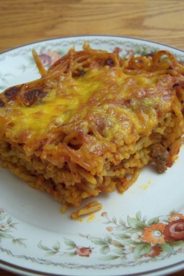 Easy Cheesy Spaghetti Bake slice on round plate with flowers