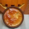 Sweet Potato Creme Brulee in round brown baking dish on striped cream place mat in from of carved pumpkin