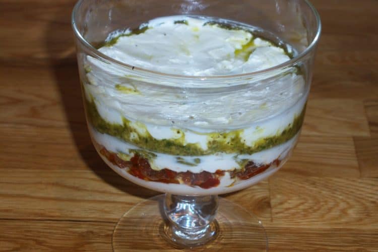 Layered Pesto Spread with sun dried tomatoes in mini glass trifle bowl