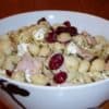 Amy's pesto pasta salad with turkey lunch meat, dried cranberries, pesto, shell pasta, mayo and goat cheese in round bowl with black flowers