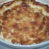 Hot Sweet Onion Dip baked with brown cheesy crust in round white baking dish