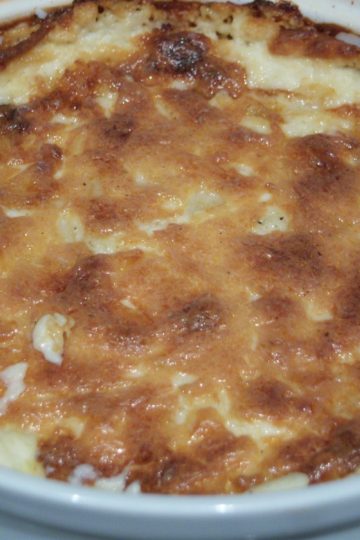 Hot Sweet Onion Dip baked with brown cheesy crust in round white baking dish