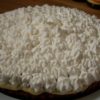 Banana cream pie with piped whip cream on large round plate