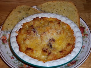 Grown up mac and cheese in mini green round pie dish on plate with garlic bread