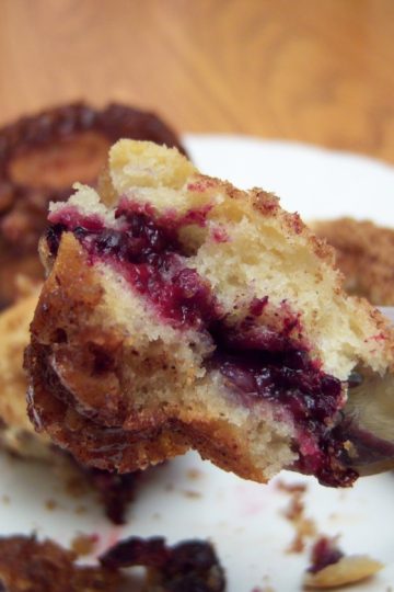 Triple Berry Coffee Cake bite on fork with small white plate in background