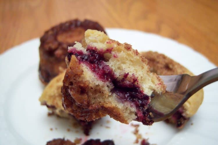 Triple Berry Coffee Cake bite on fork with small white plate in background
