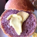Purple sweet potato roll on white plate with pat of butter
