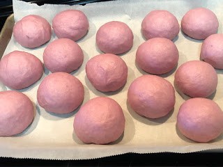 Unbaked purple sweet potato rolls on parchment lined baking sheet ready to freeze