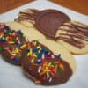Grandma's All-Occasion Sugar Cookies dipped in chocolate with sprinkles on square white plate