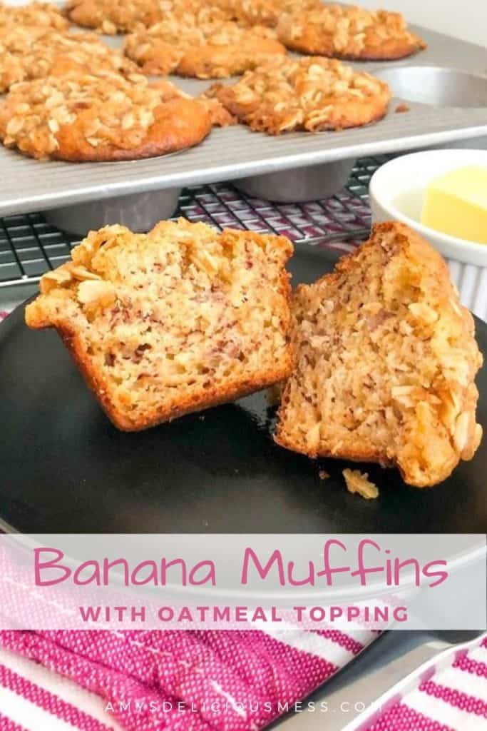 Banana muffin with oatmeal topping sliced in half on small black plate on a pink striped kitchen towel next to a small round white ramekin with butter, silver butter knife, muffin pan of banana muffins on silver cooling rack in background