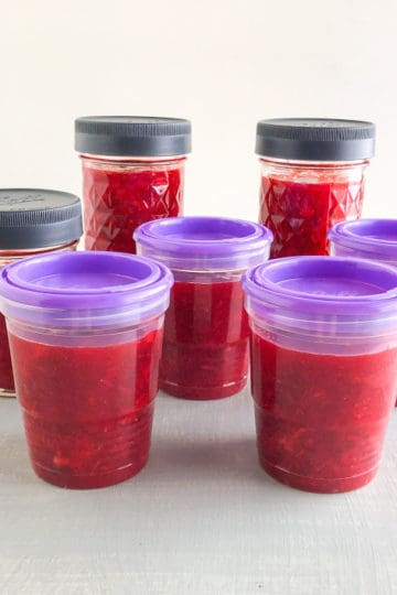 Strawberry lemon freezer jam in plastic freezer jam jars with purple lids and glass canning jars with gray lids