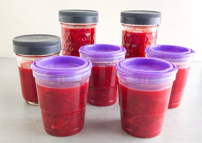 Strawberry lemon freezer jam in plastic freezer jam jars with purple lids and glass canning jars with gray lids