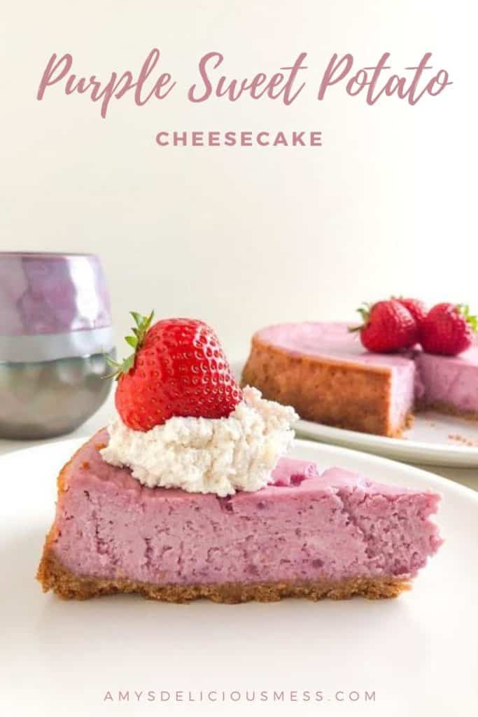 Purple sweet potato cheesecake slice on small round white plate topped with whipped cream and a whole strawberry, whole cheesecake in background on round white plate topped with whole strawberries, purple and gray coffee cup in background