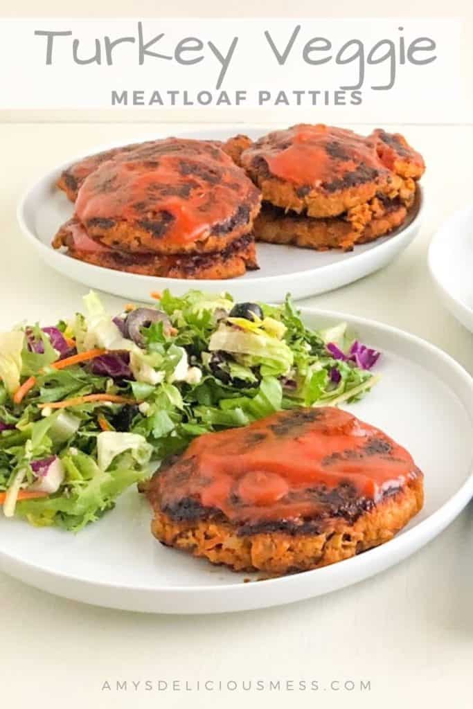 Turkey veggie meatloaf patty on round white plate with a green salad, round white plate in the background with additional turkey veggie meatloaf patties.