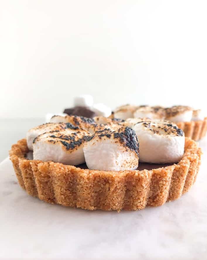 S'mores tart with toasted marshmallows on a marble board