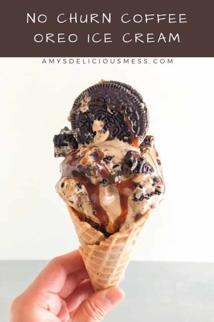 Hand holding a waffle cone with ice cream, topped with whole Oreo and salted caramel sauce.