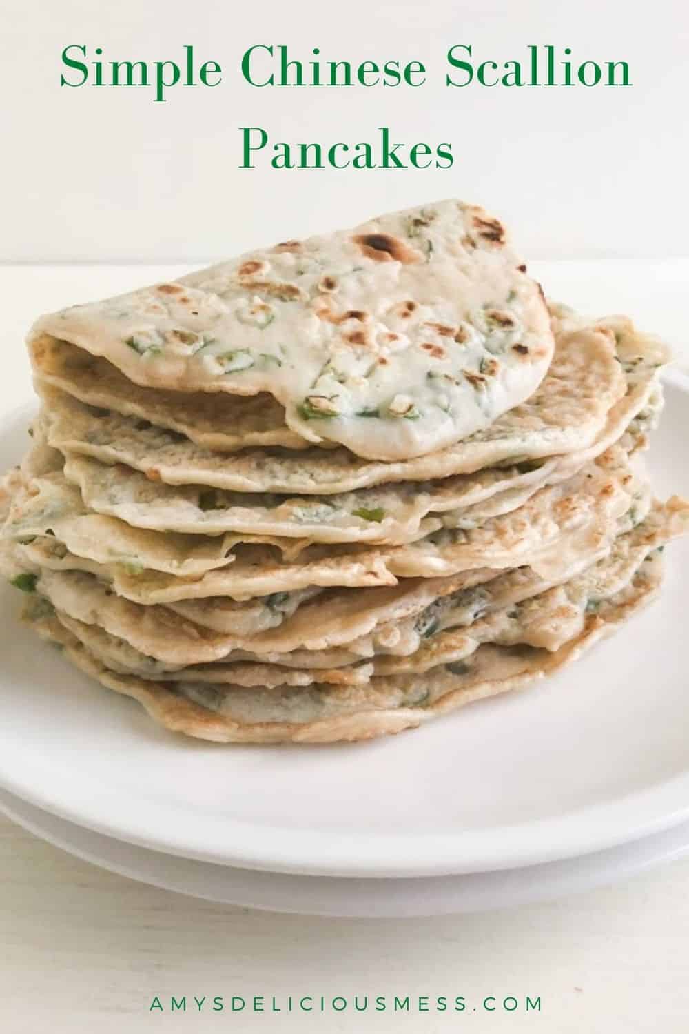 Stack of green onion pancakes on round white plate with top pancake folded over