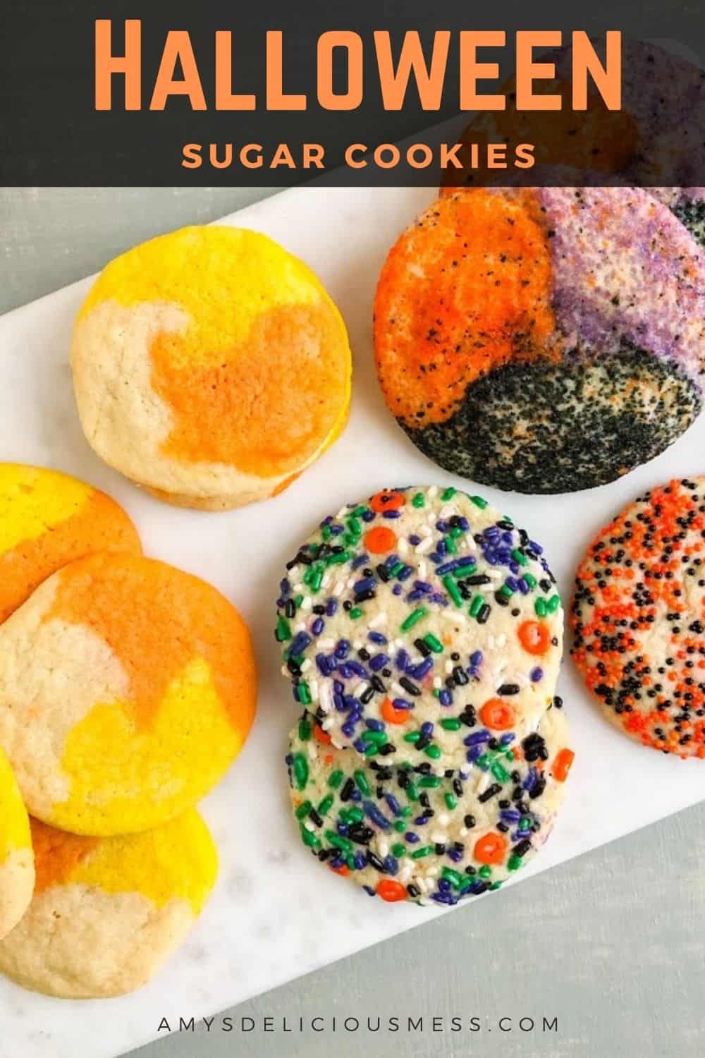 "Candy corn" colored cookies, Halloween sprinkle cookies, orange and black nonpareil coated sugar cookie, orange, black, and purple sanding sugar coated cookies on marble board. 