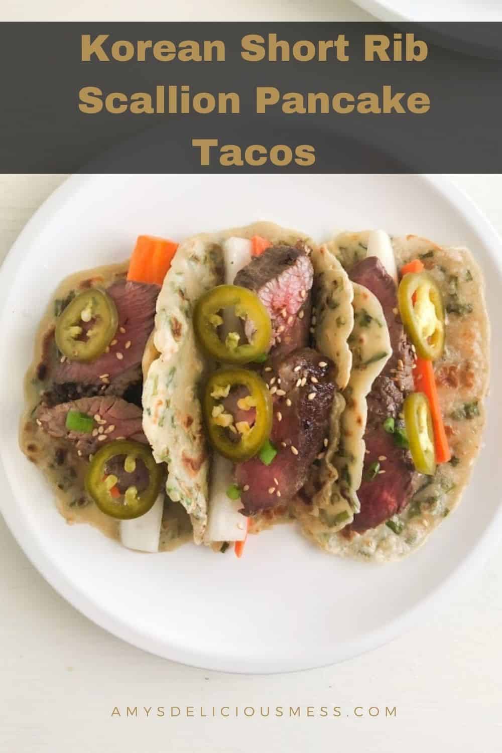 3 scallion pancake tacos on round white plate. Tacos filled with sliced short ribs, pickled daikon, carrot, and jalapenos.