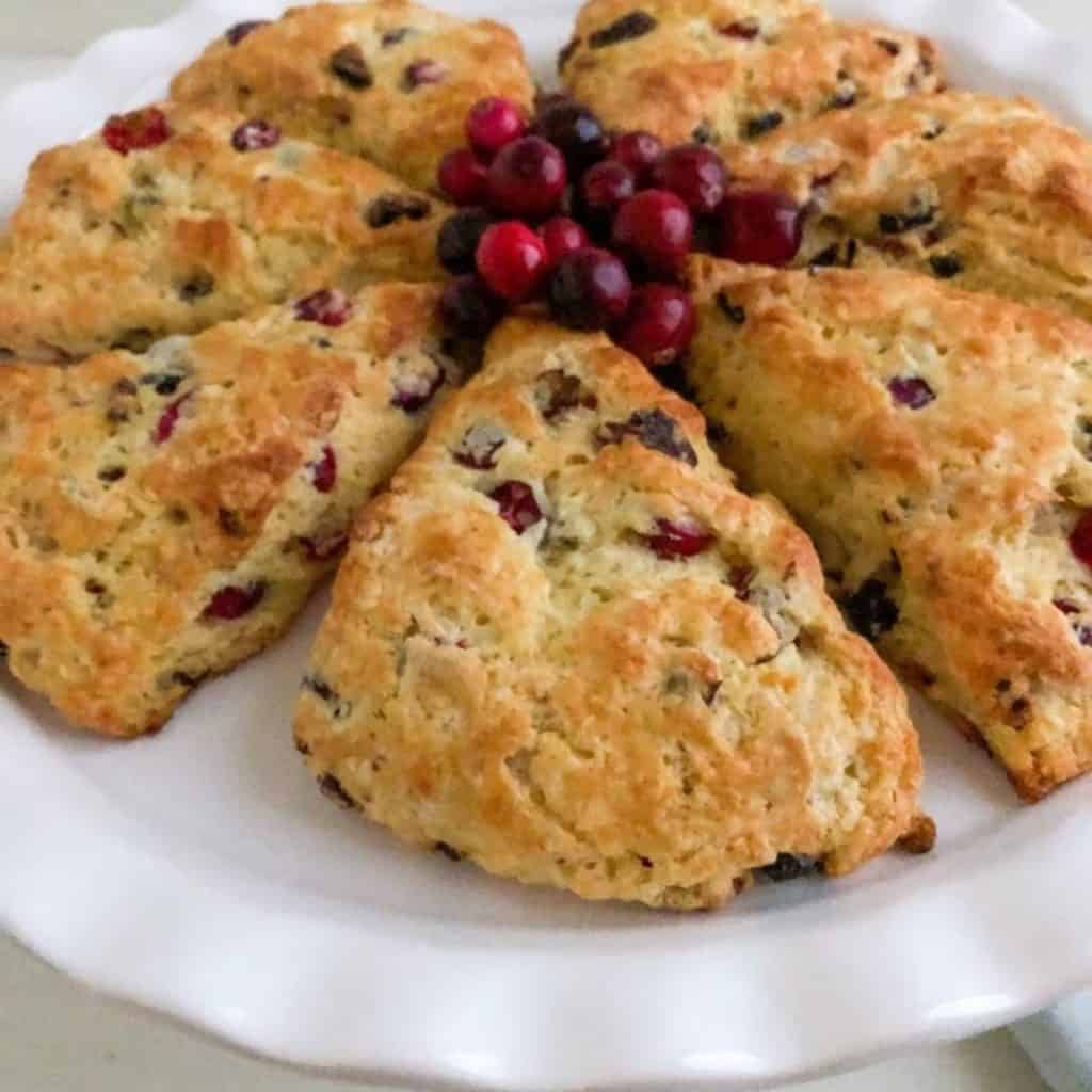 Scones on white cake stand with fresh cranberries in the middle of the circle of the scones.